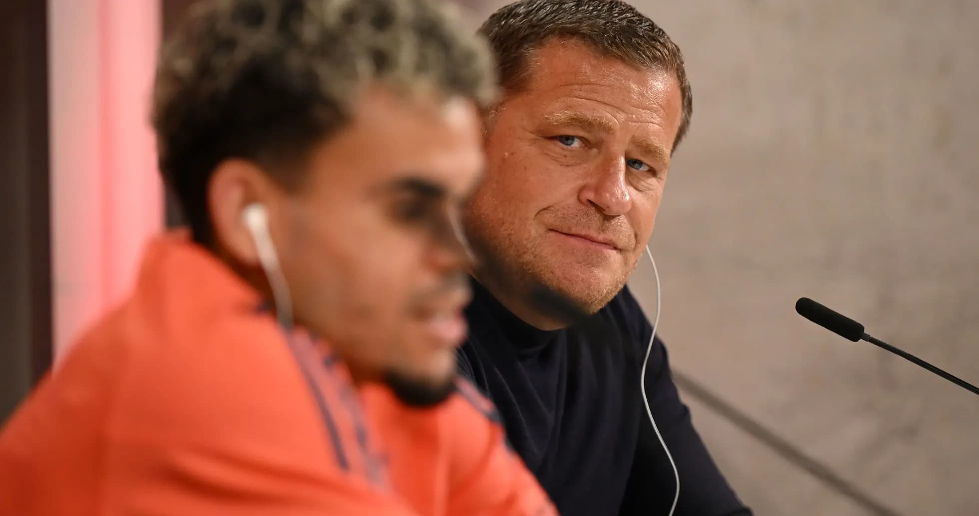Two men seated at press conference table Two men seated at press conference table
