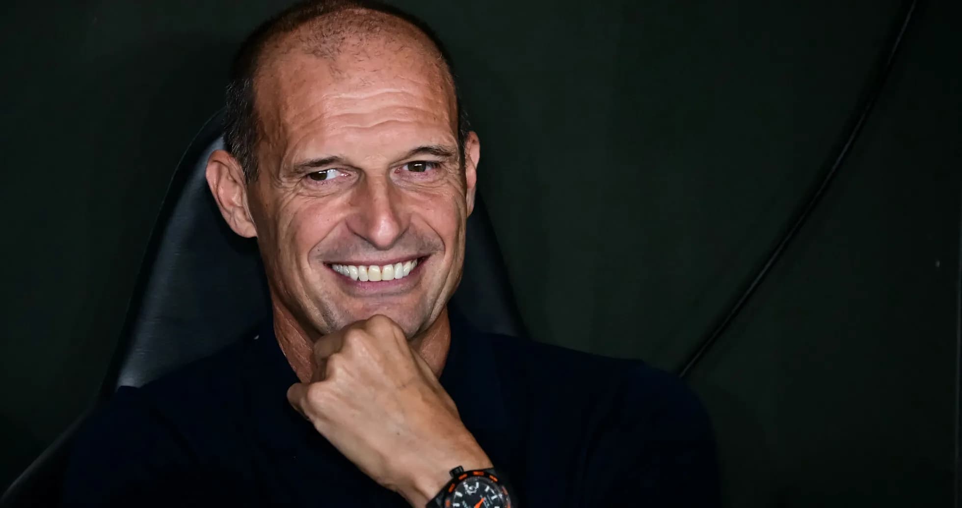 Smiling coach seated, hand on chin Smiling coach seated, hand on chin