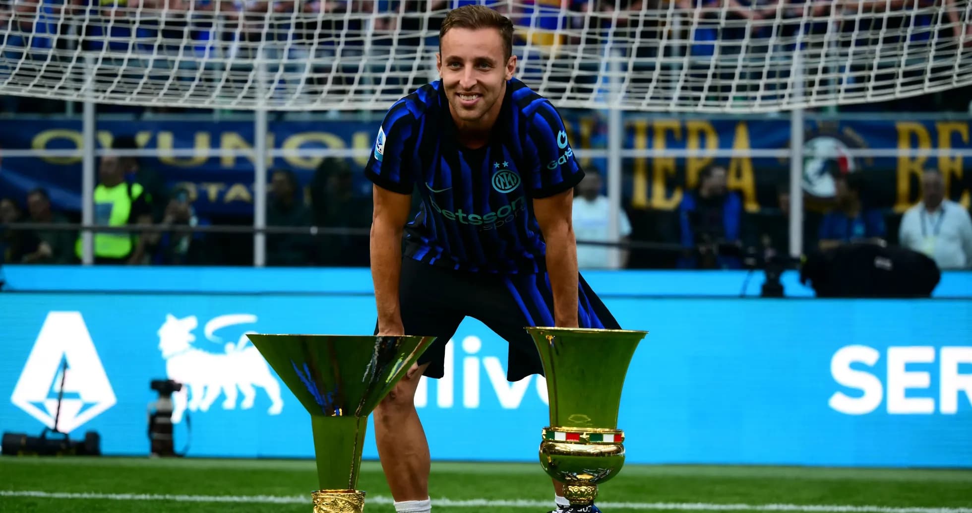 Player celebrating with two trophies on the field Player celebrating with two trophies on the field