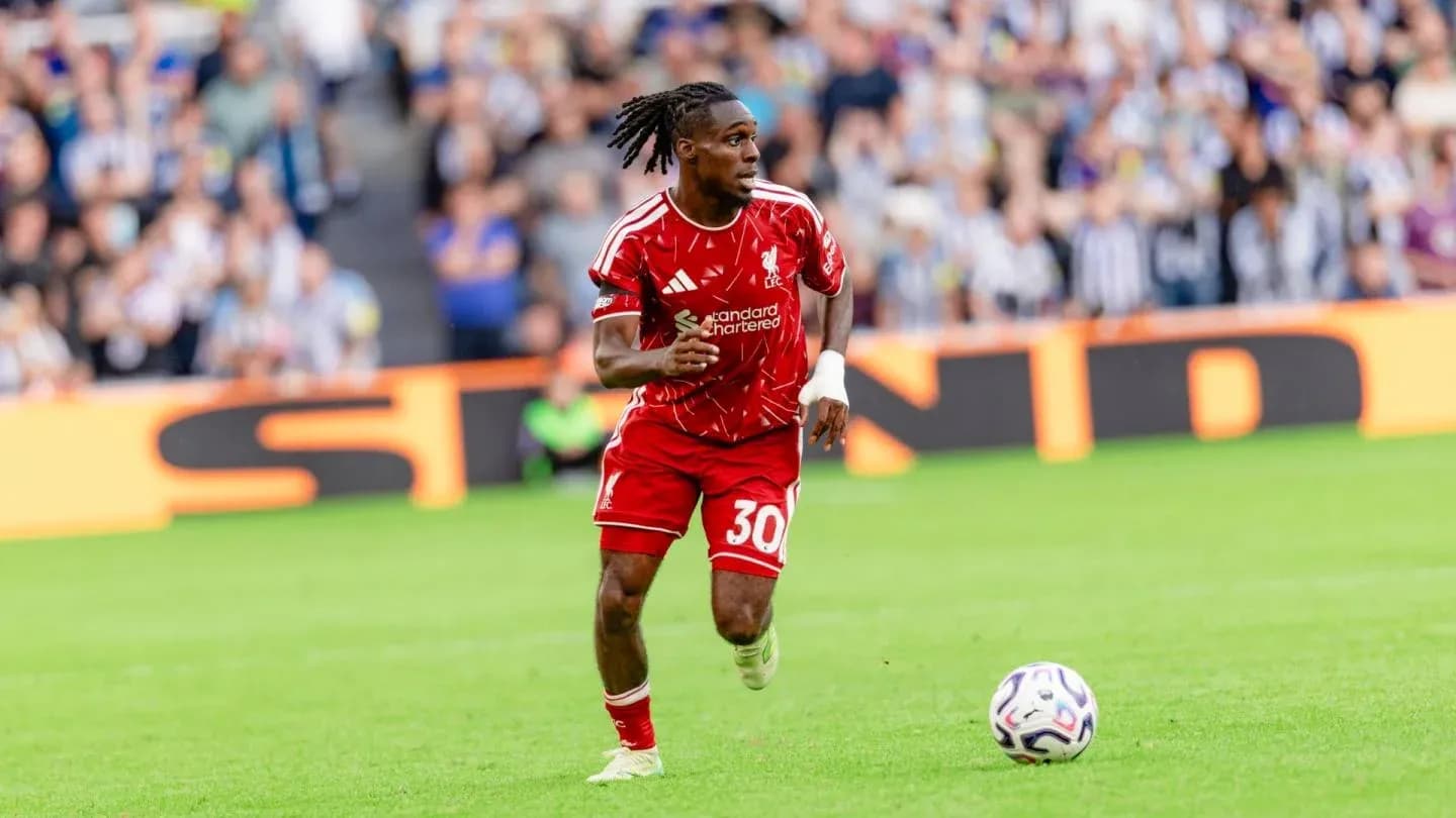 Player in red kit running with soccer ball on pitch Player in red kit running with soccer ball on pitch