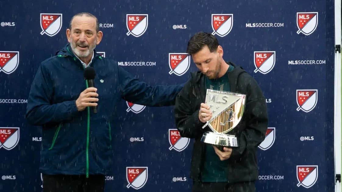 MLS official presenting trophy to player in rain MLS official presenting trophy to player in rain