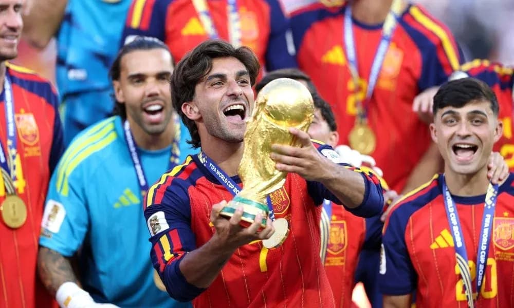 Player celebrating with FIFA World Cup trophy surrounded by teammates Player celebrating with FIFA World Cup trophy surrounded by teammates