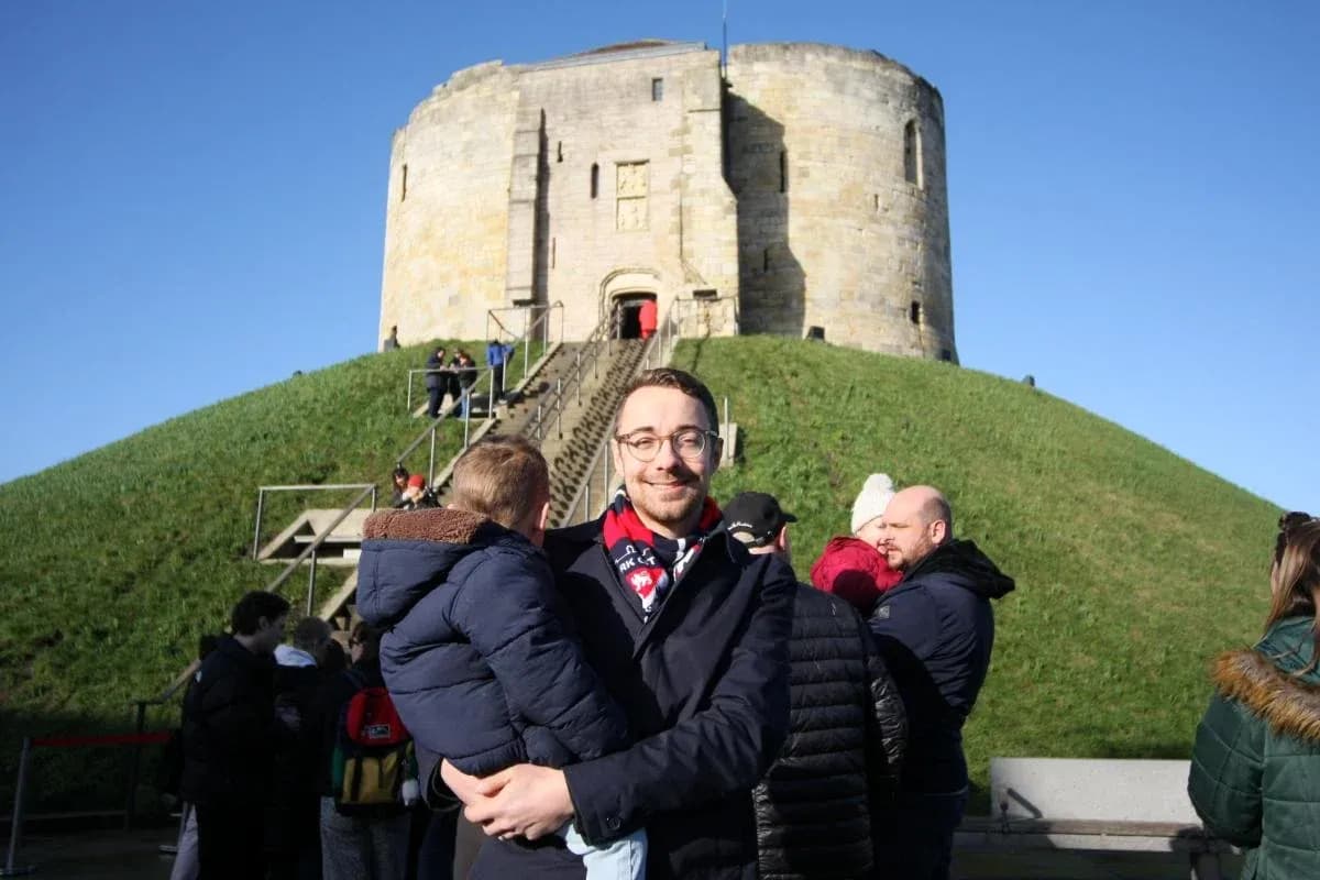 Man holding child in front of historic tower Man holding child in front of historic tower