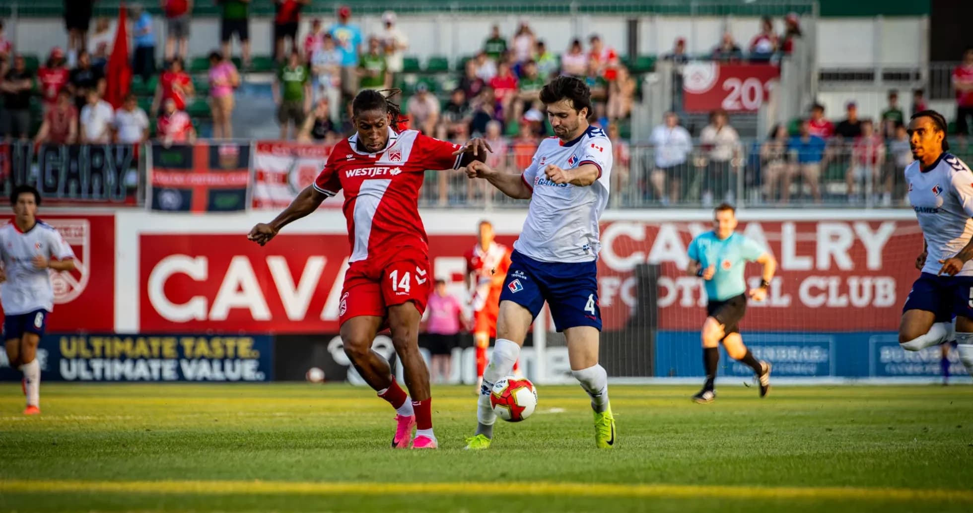 Cavalry FC player challenging Supra du Quebec opponent Cavalry FC player challenging Supra du Quebec opponent