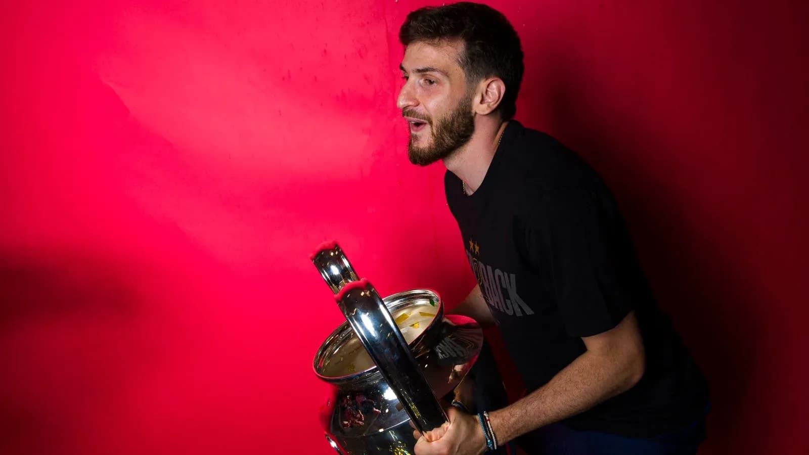 Player holding a trophy against a pink background Player holding a trophy against a pink background