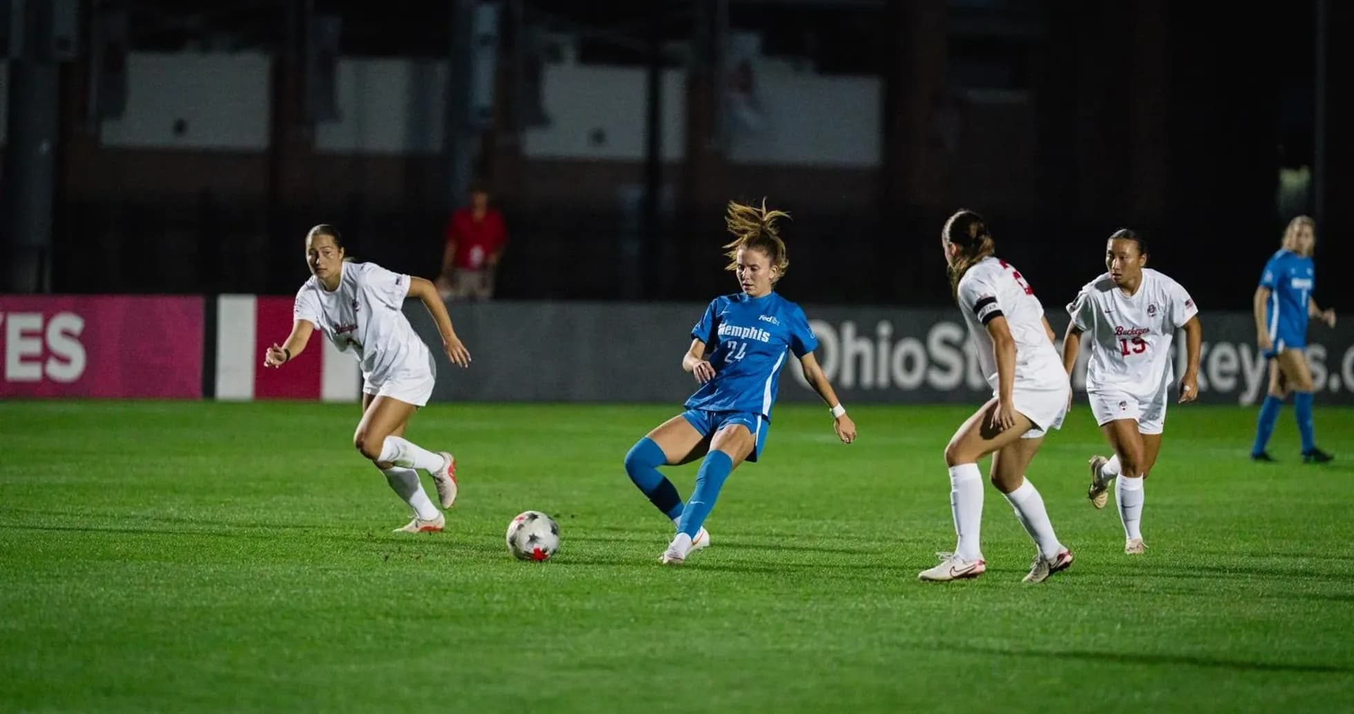 Player in blue dribbling past defenders in white Player in blue dribbling past defenders in white