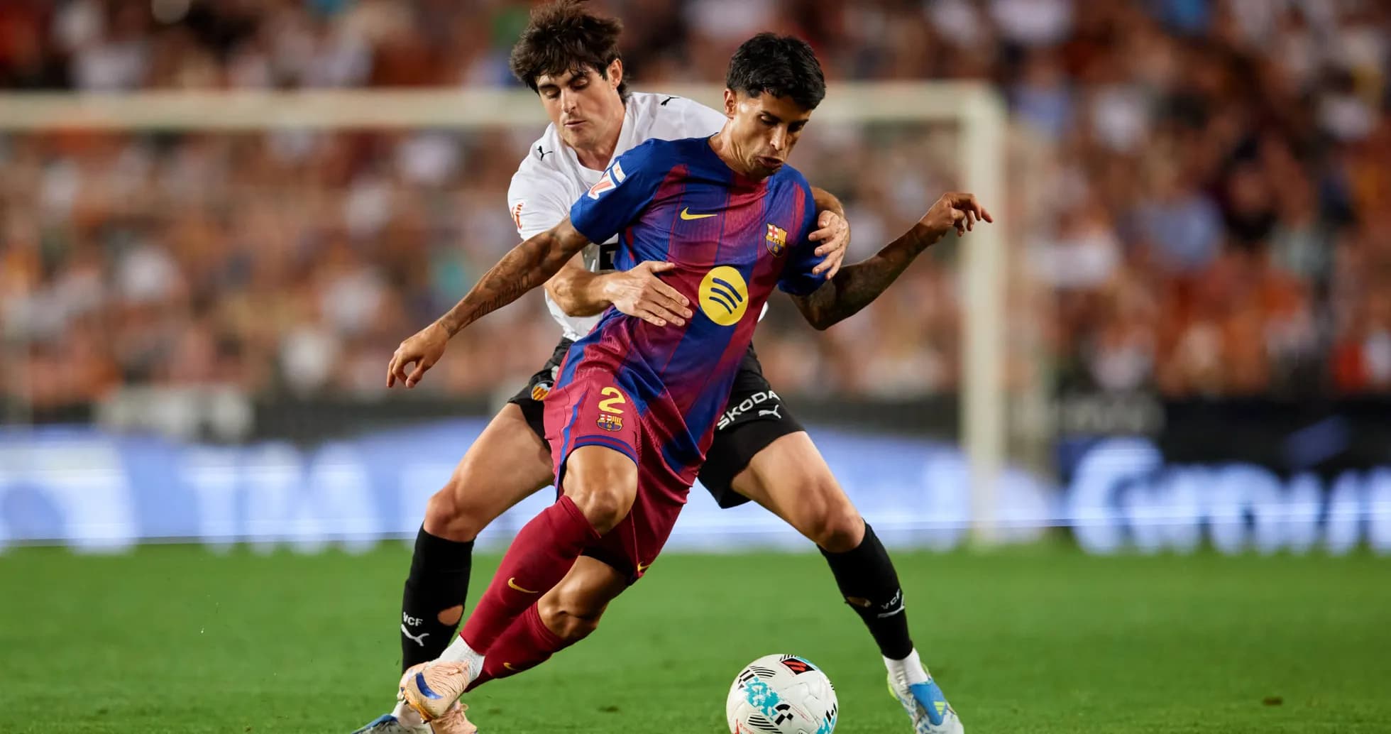 Barcelona player tackled by Valencia opponent during match Barcelona player tackled by Valencia opponent during match