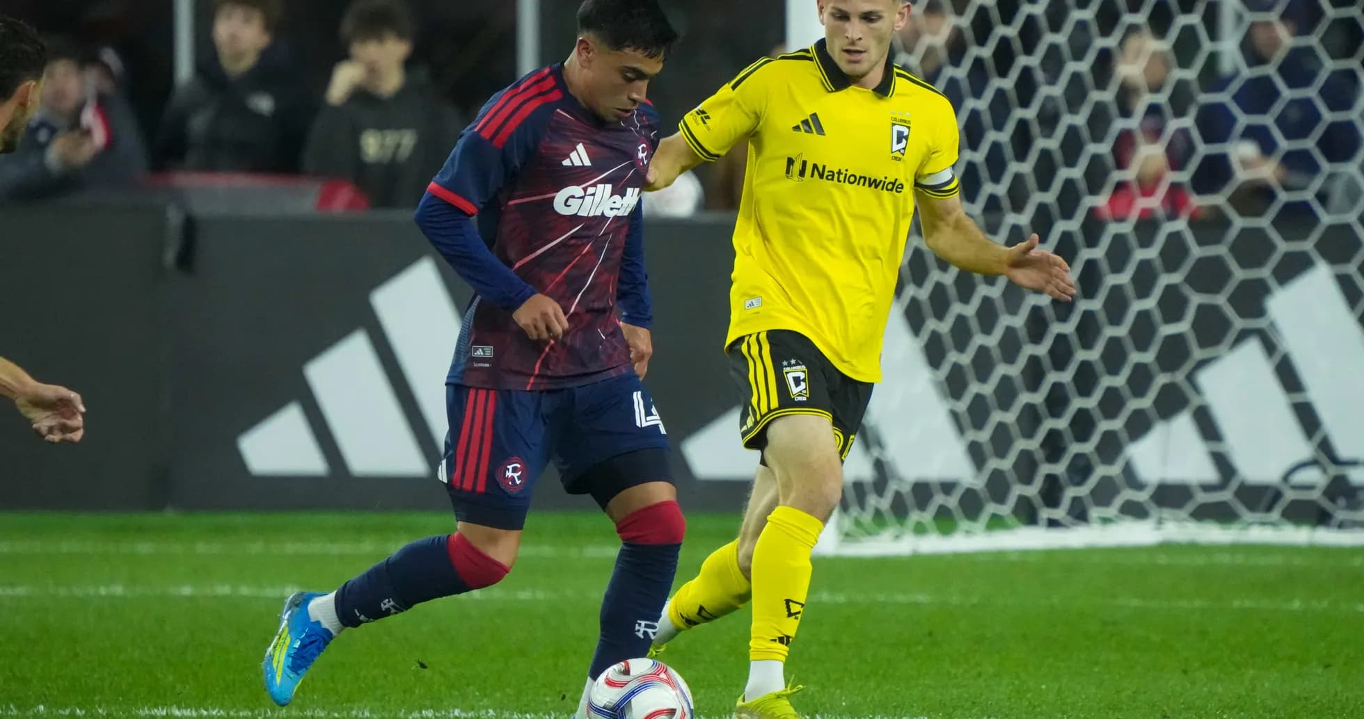 Columbus Crew player challenging New England Revolution player Columbus Crew player challenging New England Revolution player