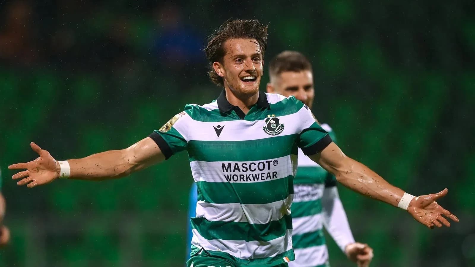 Player celebrating a goal in a green striped jersey Player celebrating a goal in a green striped jersey