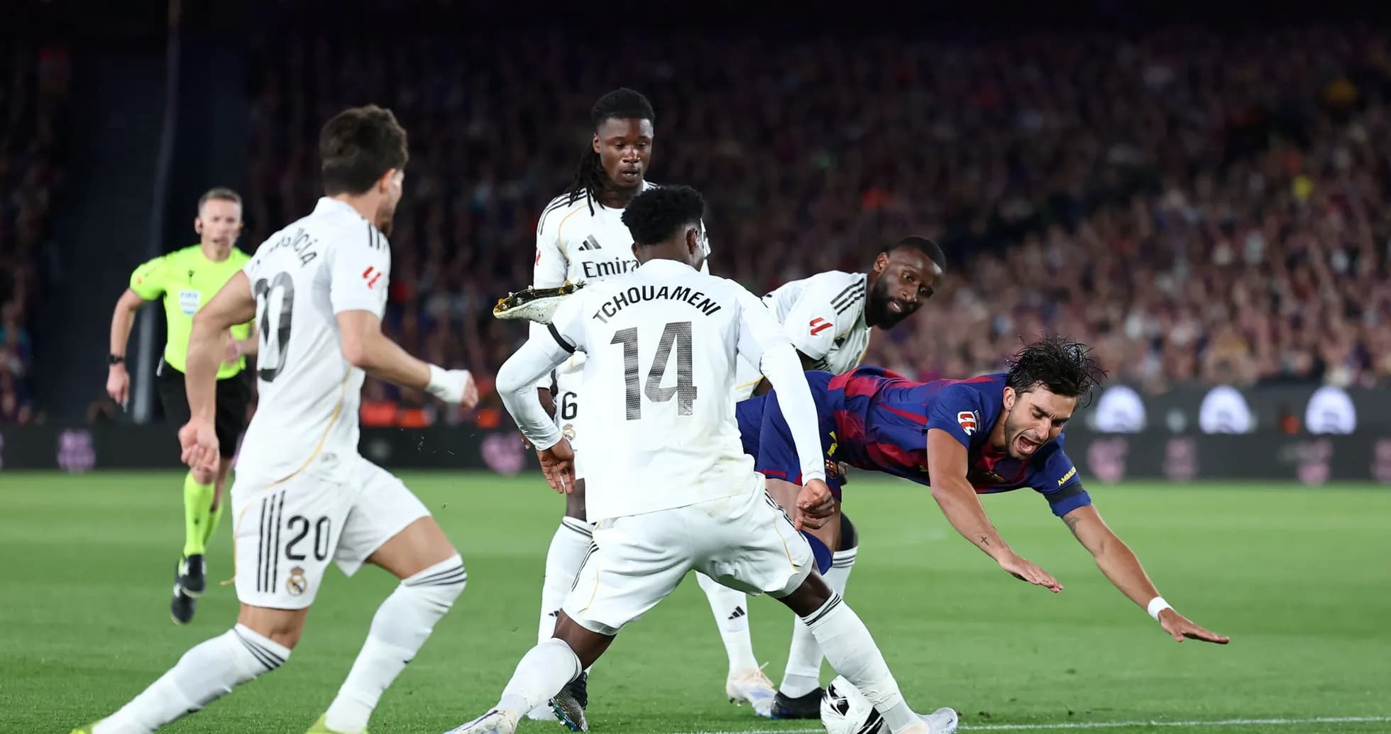 Barcelona player falling while challenged by Real Madrid defenders Barcelona player falling while challenged by Real Madrid defenders