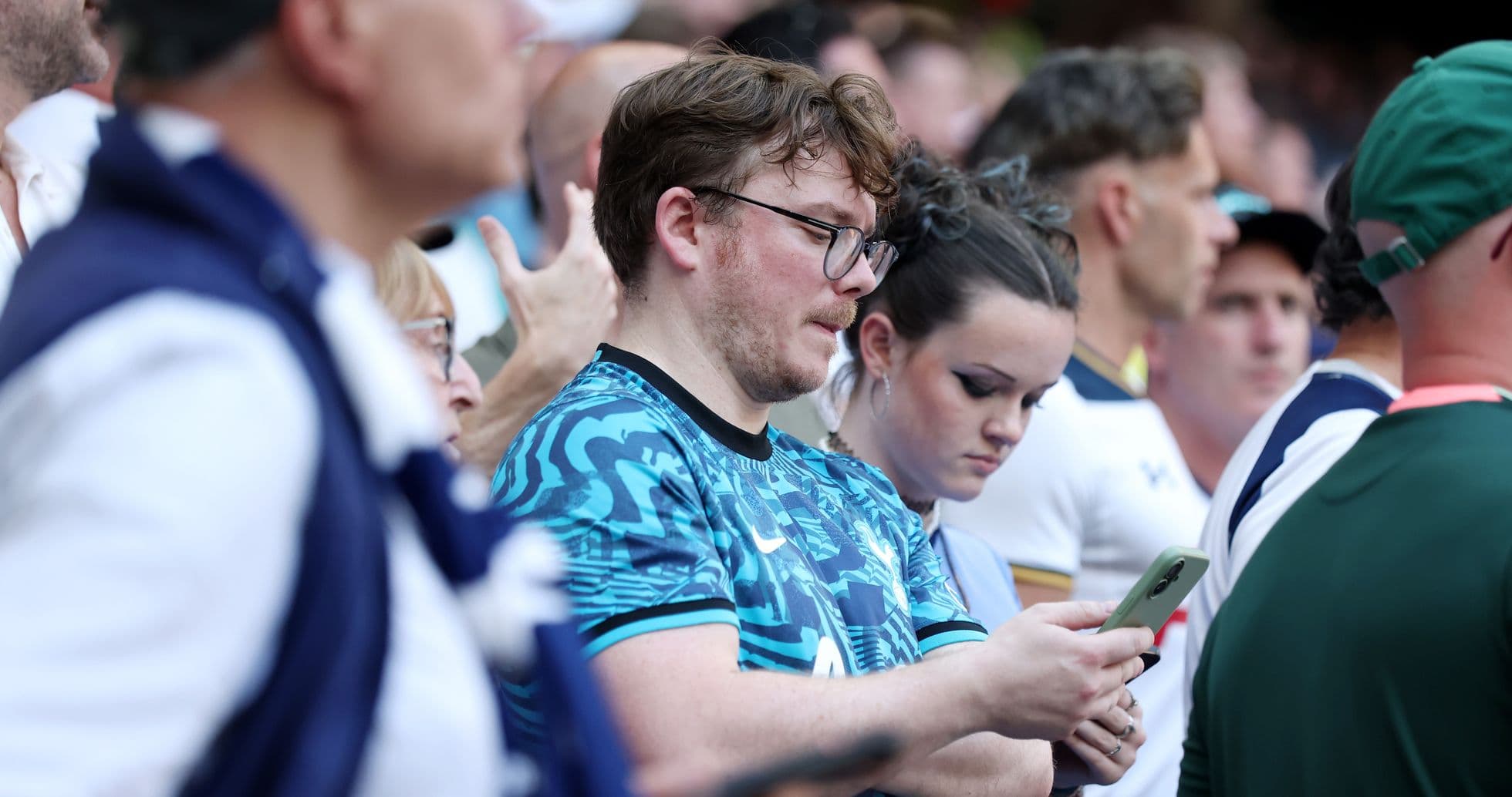 Fans looking at their phones in crowded stadium Fans looking at their phones in crowded stadium