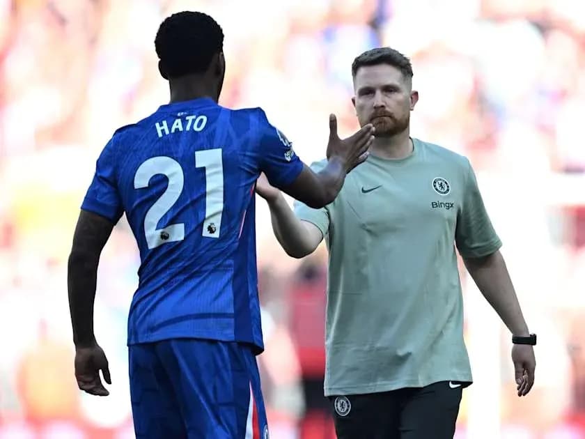 Player in blue jersey greeting staff member on pitch Player in blue jersey greeting staff member on pitch