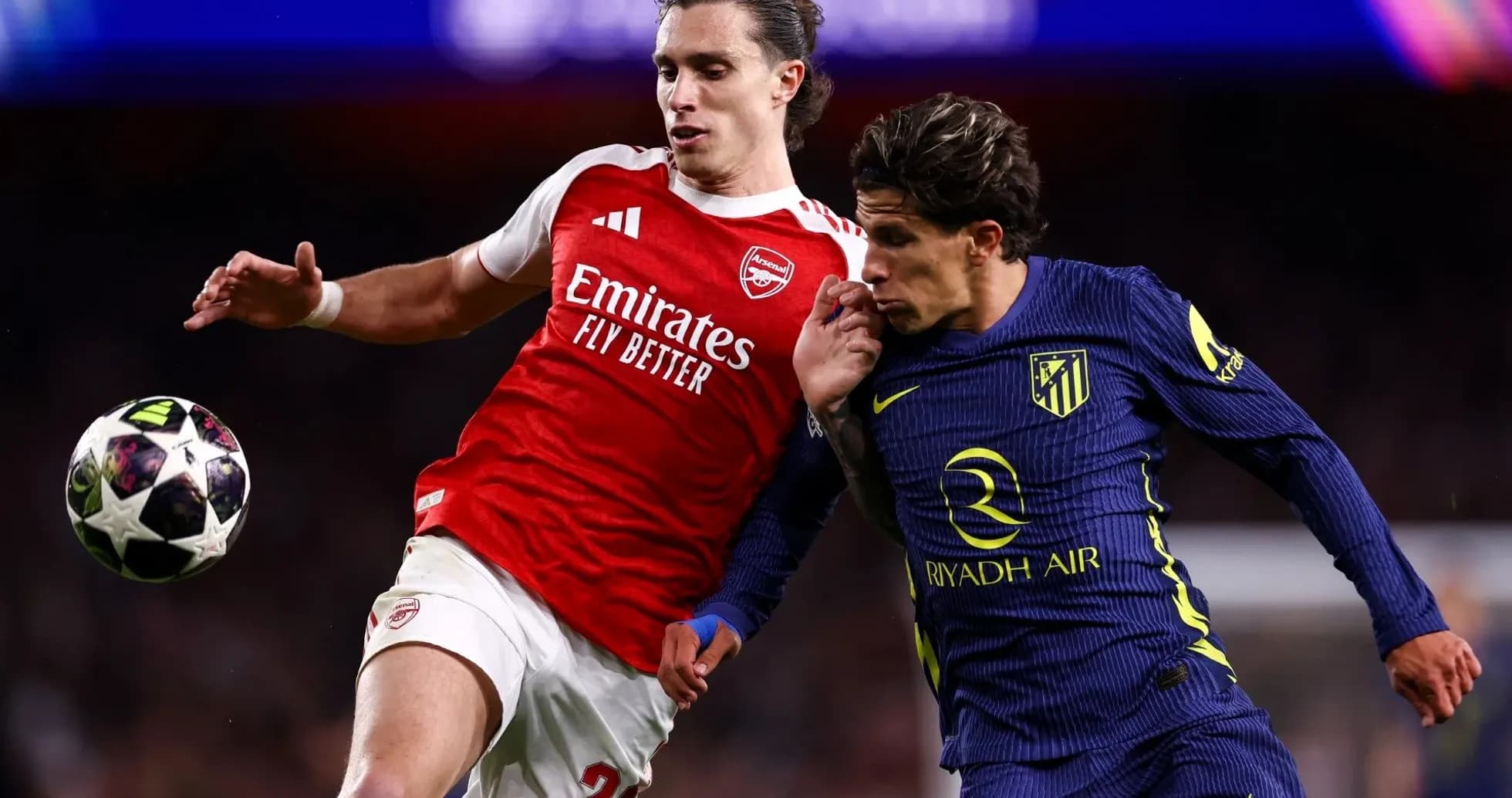 Arsenal player challenges Atletico player for the ball Arsenal player challenges Atletico player for the ball