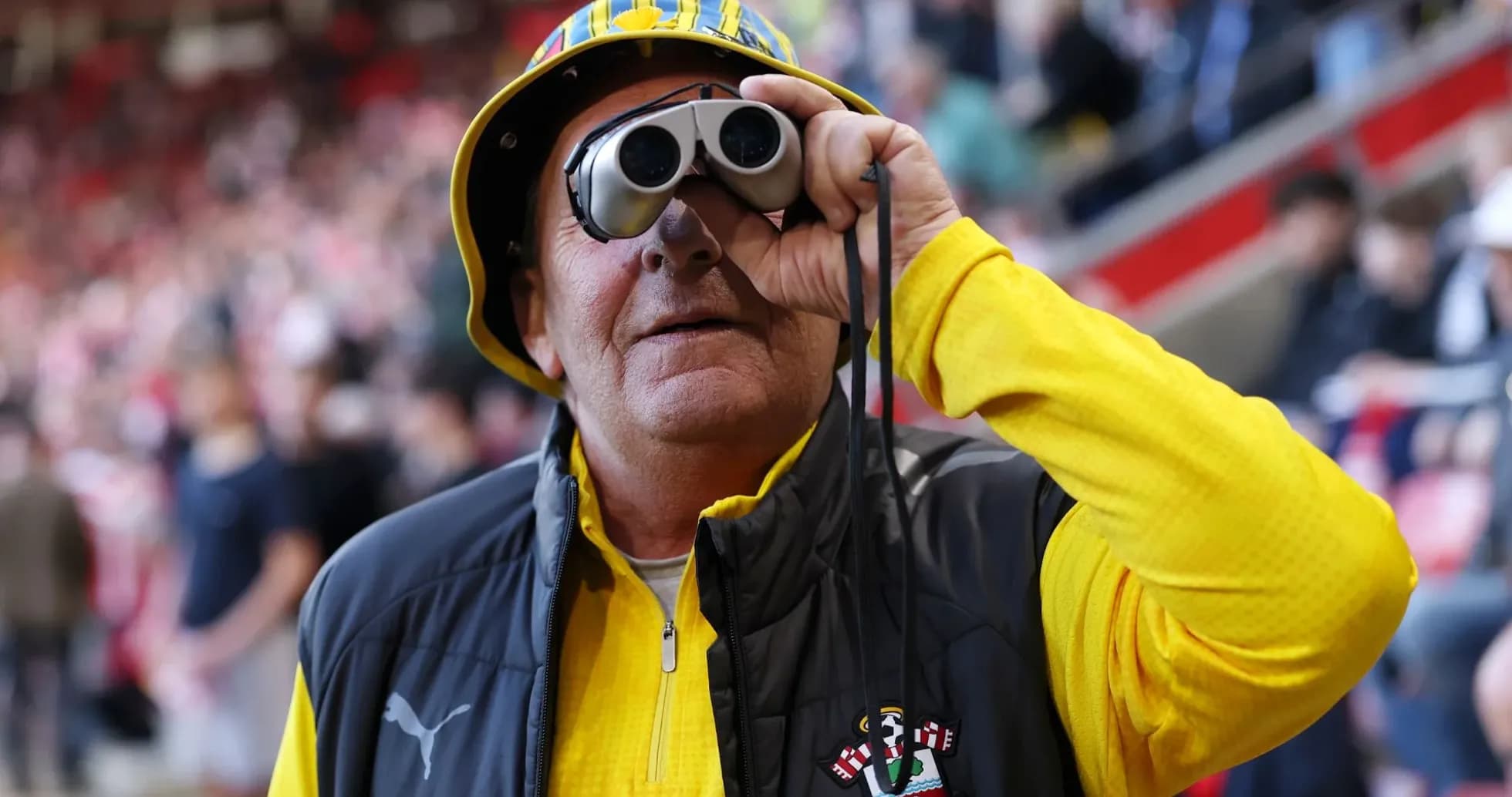 Fan wearing binoculars and a hat at stadium Fan wearing binoculars and a hat at stadium