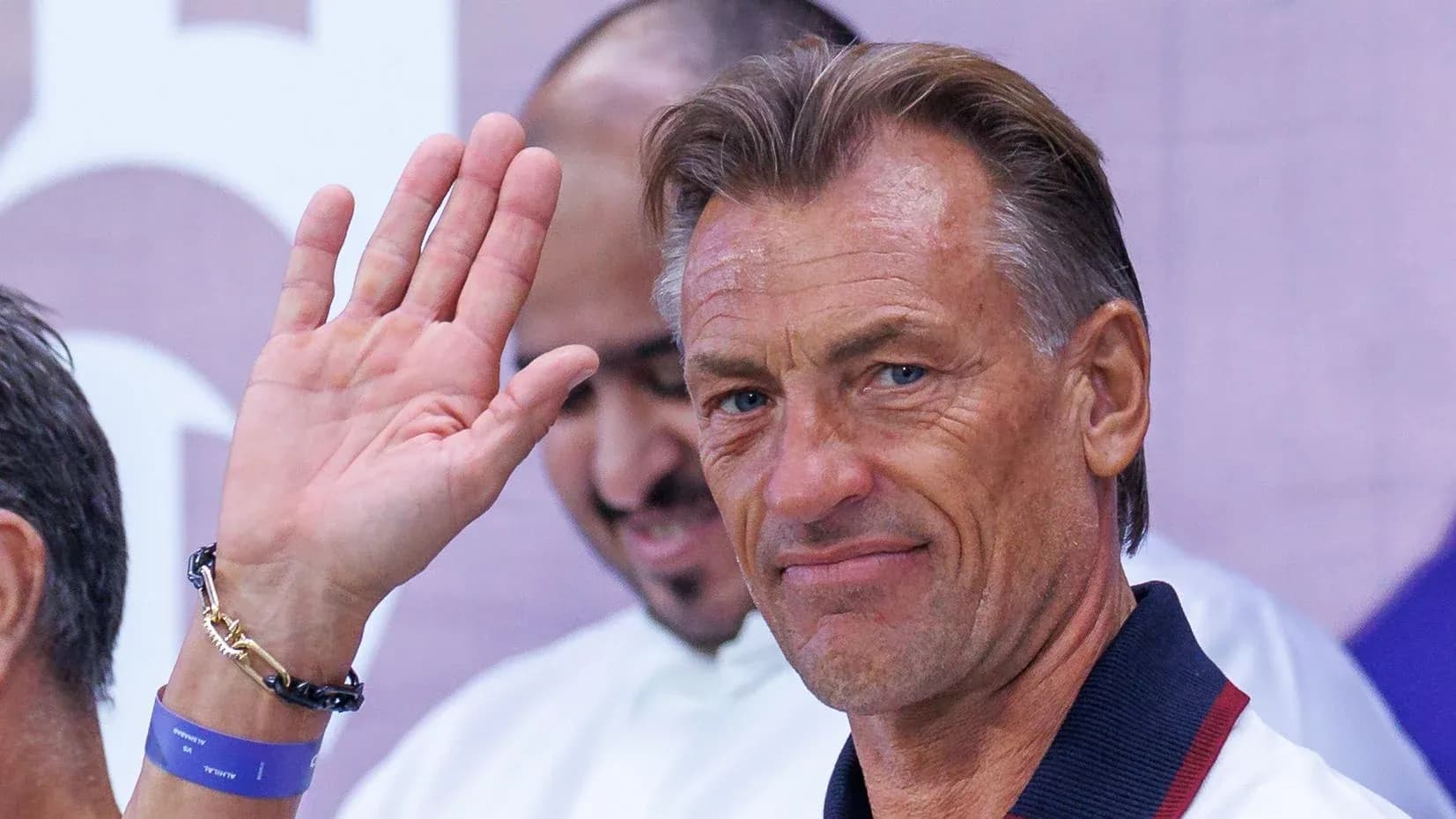 Coach waving during a press event or appearance Coach waving during a press event or appearance