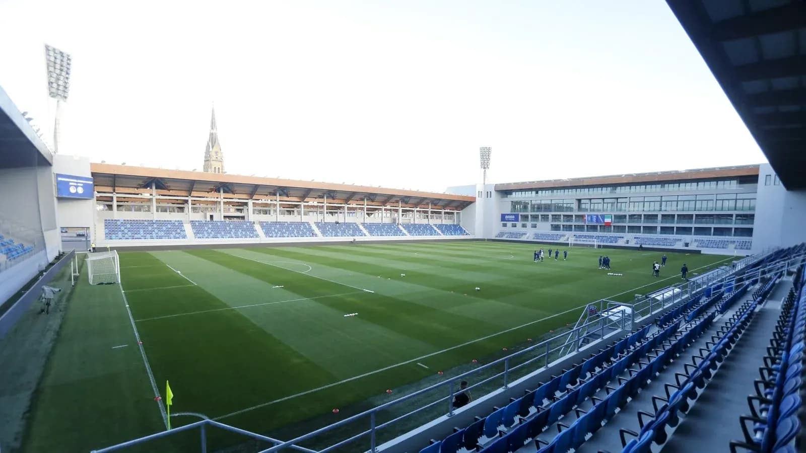 Empty football stadium with players training on field Empty football stadium with players training on field