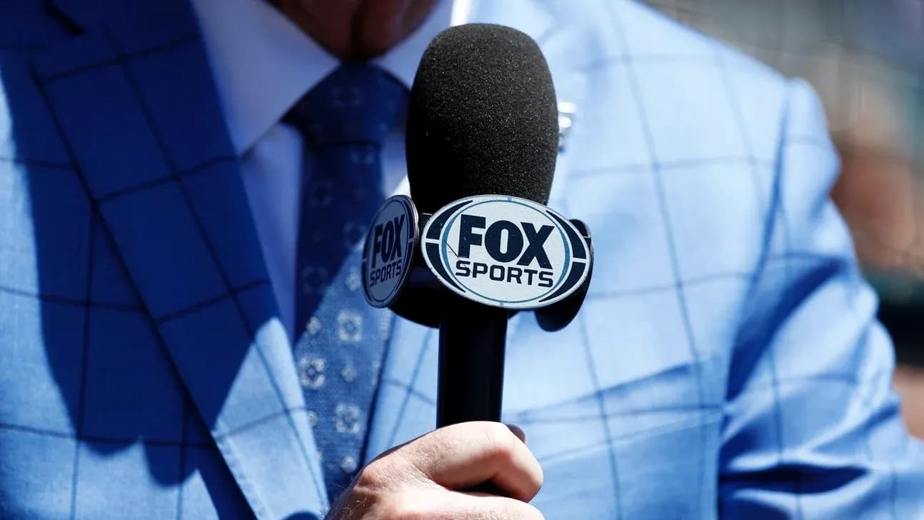 Person holding a FOX Sports microphone in blue suit Person holding a FOX Sports microphone in blue suit