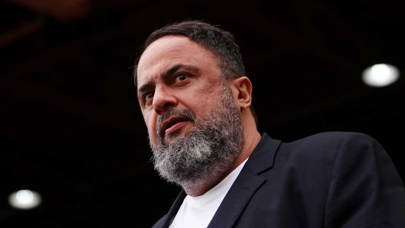 Person speaking at an event with serious expression Person speaking at an event with serious expression