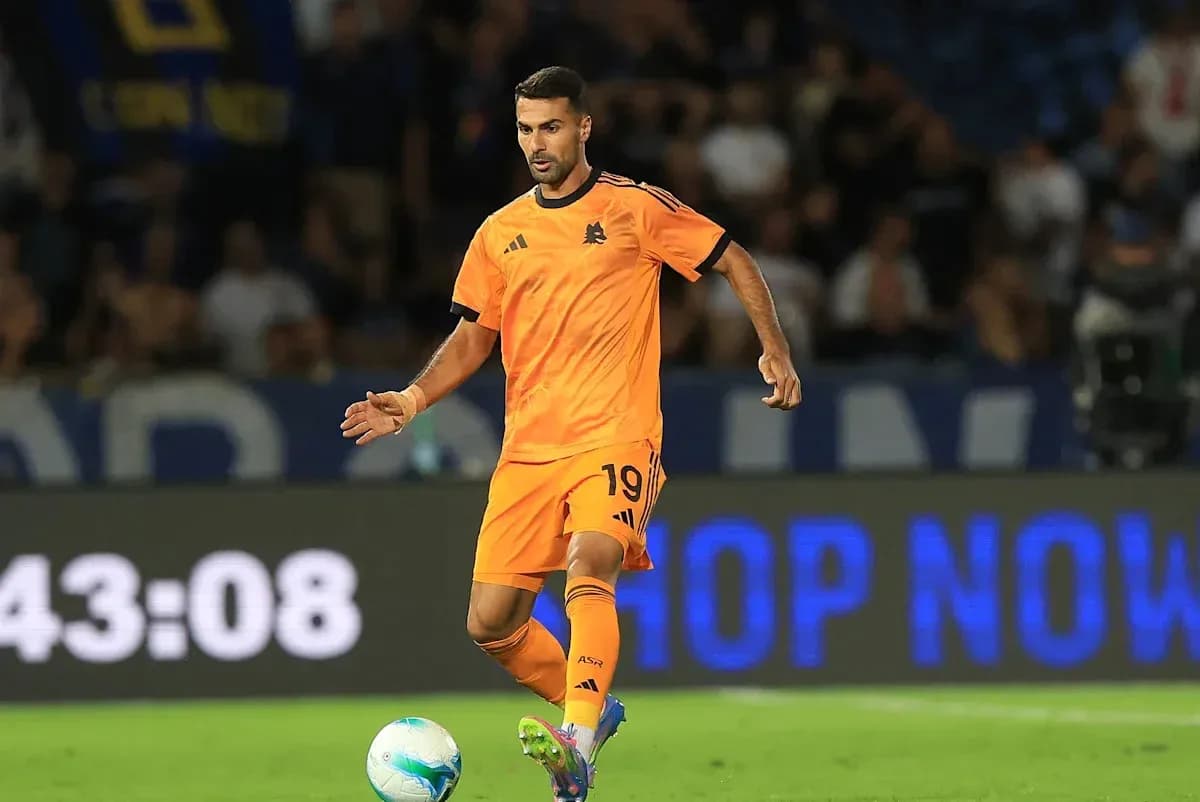 Player in orange kit dribbling ball on field Player in orange kit dribbling ball on field