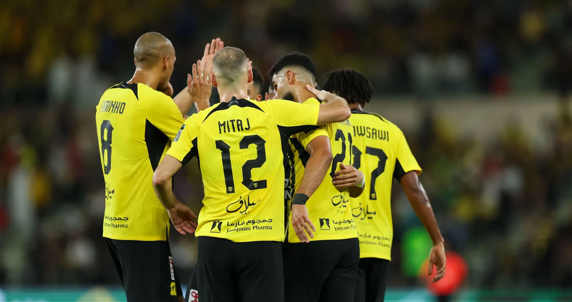 Players celebrating a goal in yellow jerseys Players celebrating a goal in yellow jerseys