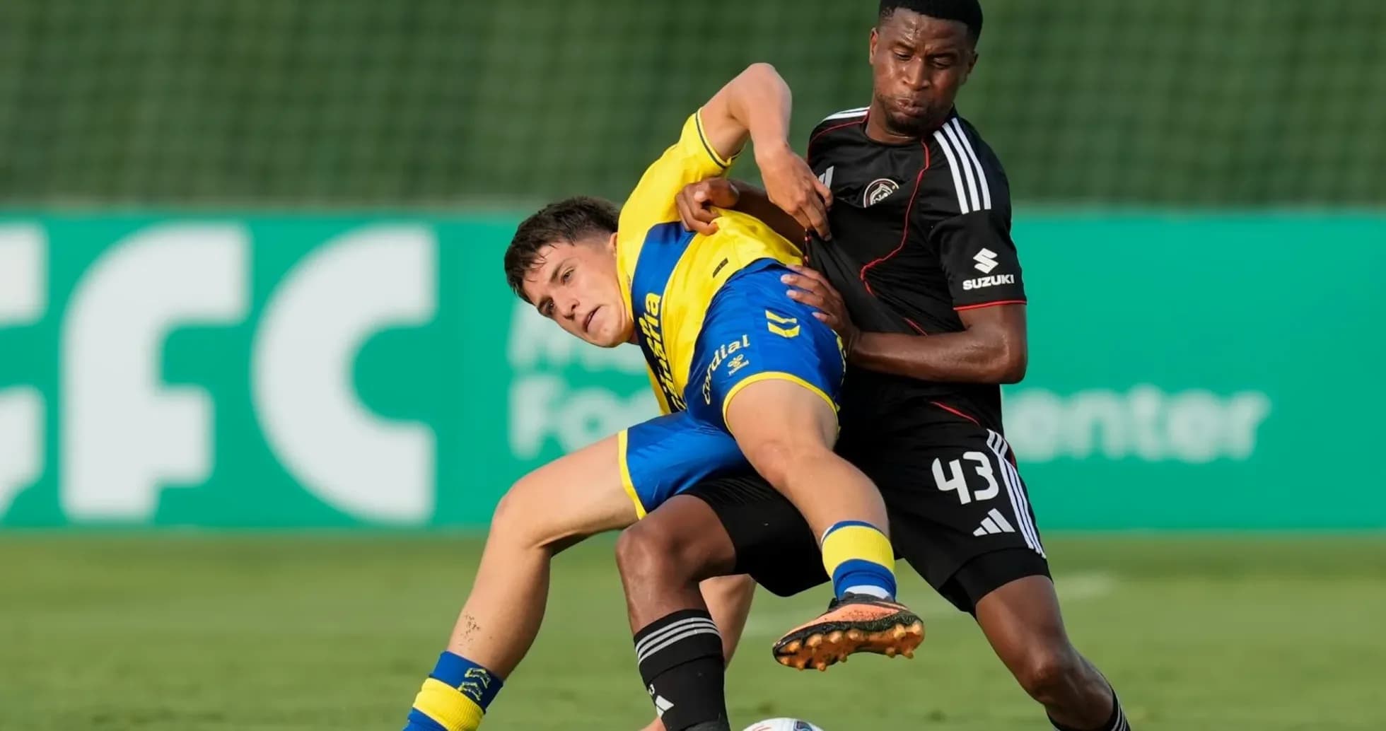 Player in yellow being tackled by opponent in black Player in yellow being tackled by opponent in black