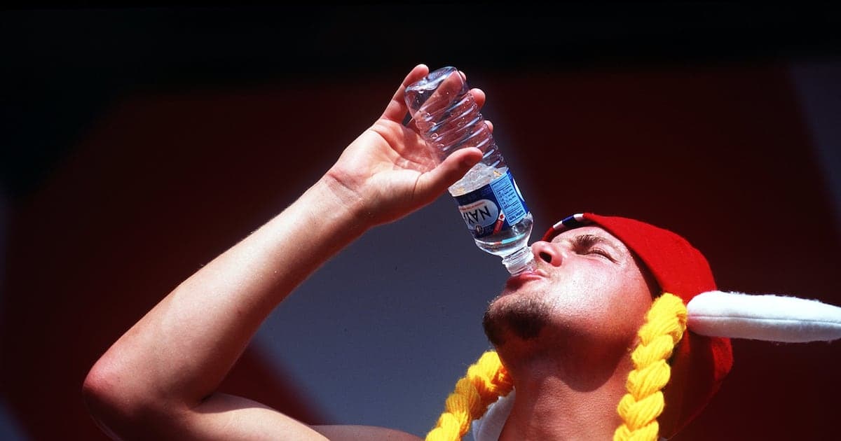 Person in hat drinking water from bottle Person in hat drinking water from bottle