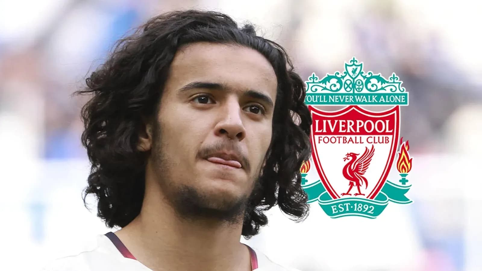 Player with curly hair near Liverpool FC logo Player with curly hair near Liverpool FC logo