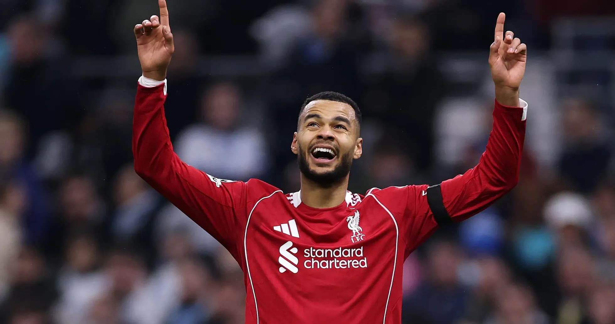 Player celebrating with arms raised in Liverpool kit Player celebrating with arms raised in Liverpool kit