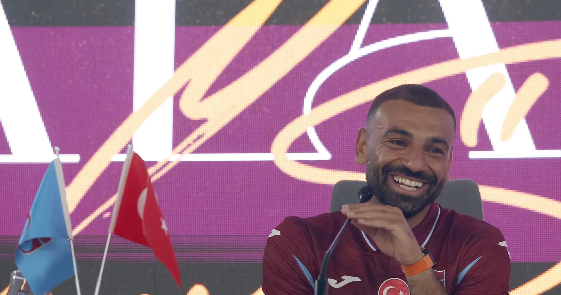 Football player speaking at press conference with flags Football player speaking at press conference with flags