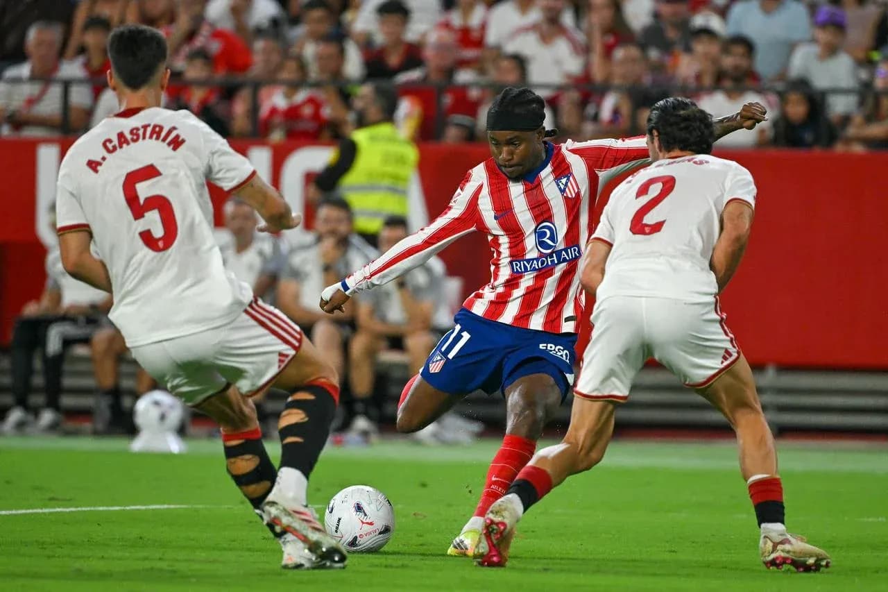 Atletico Madrid player dribbling past Sevilla defenders Atletico Madrid player dribbling past Sevilla defenders