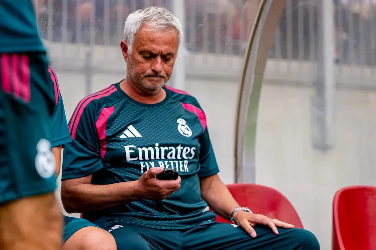 Coach sitting on bench using mobile phone Coach sitting on bench using mobile phone