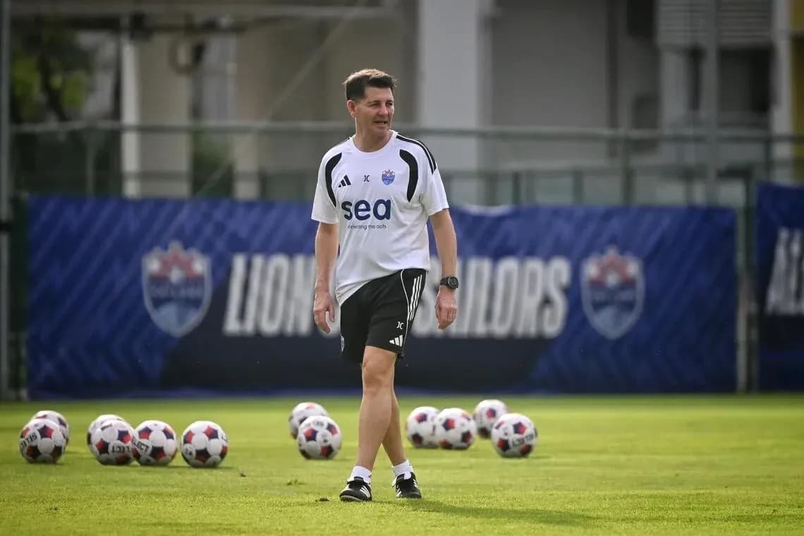 Coach walking on training pitch with soccer balls Coach walking on training pitch with soccer balls