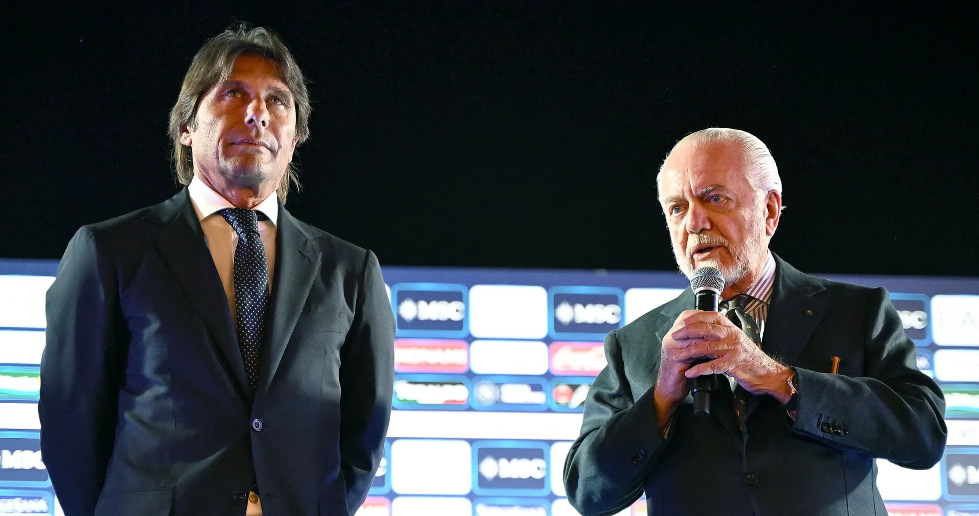 Two men speaking at a press conference event Two men speaking at a press conference event