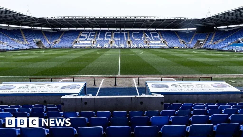 Empty football stadium with blue seating and pitch Empty football stadium with blue seating and pitch