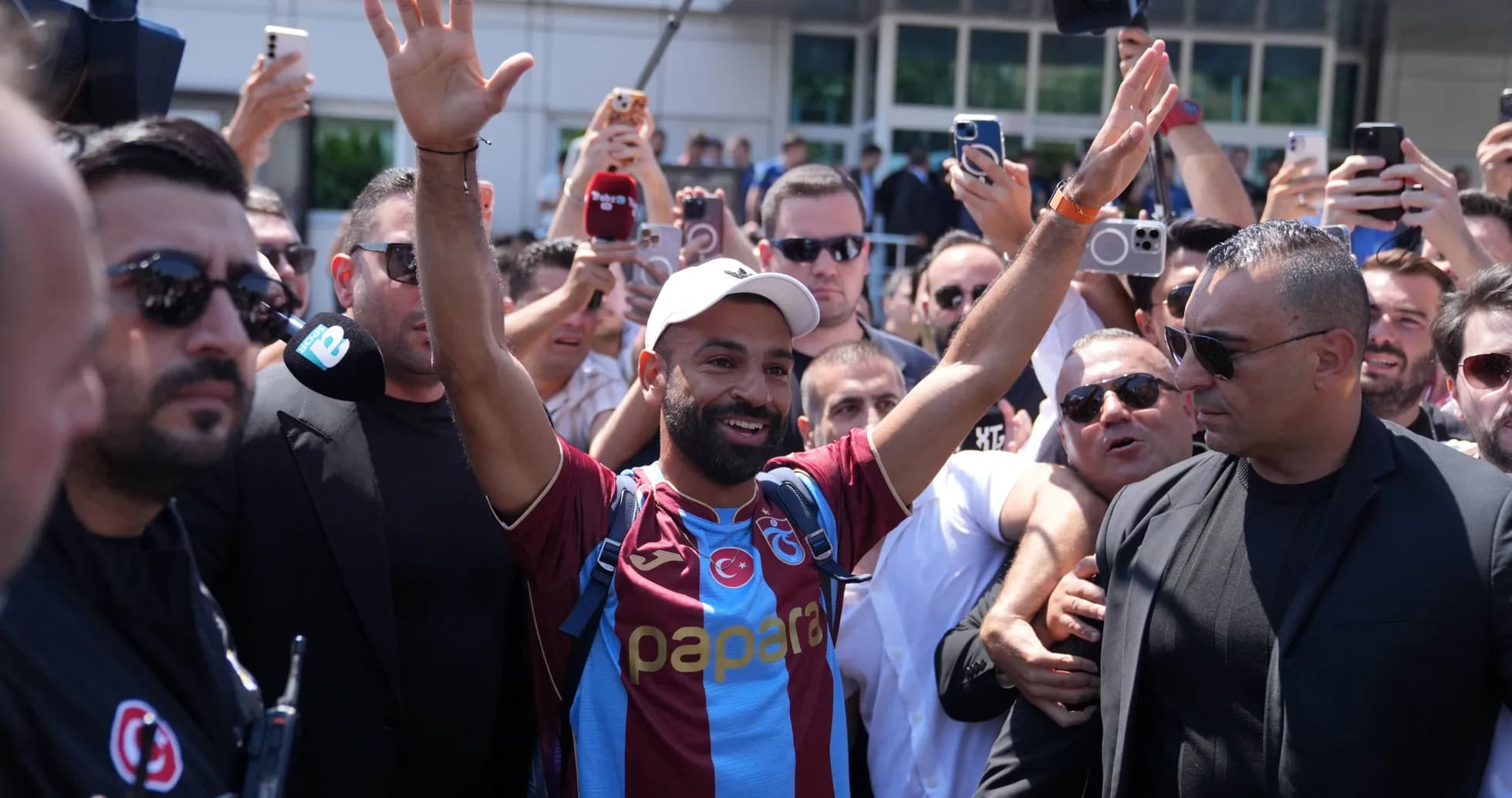 Player greeting fans surrounded by media and security Player greeting fans surrounded by media and security