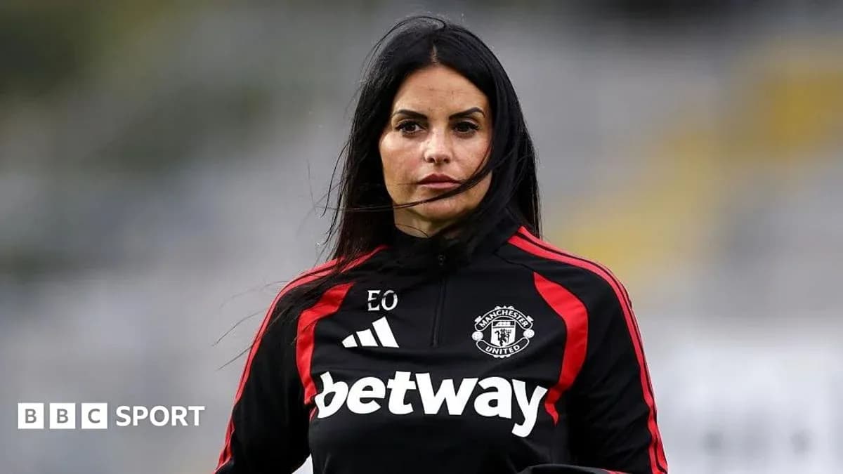 Coach in Manchester United training attire on field Coach in Manchester United training attire on field