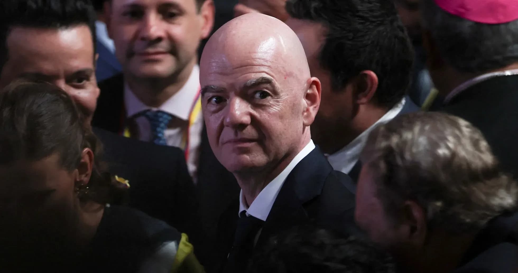 Man in suit surrounded by people at event Man in suit surrounded by people at event