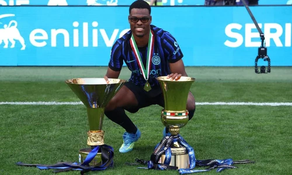 Player celebrating with two trophies on the field Player celebrating with two trophies on the field
