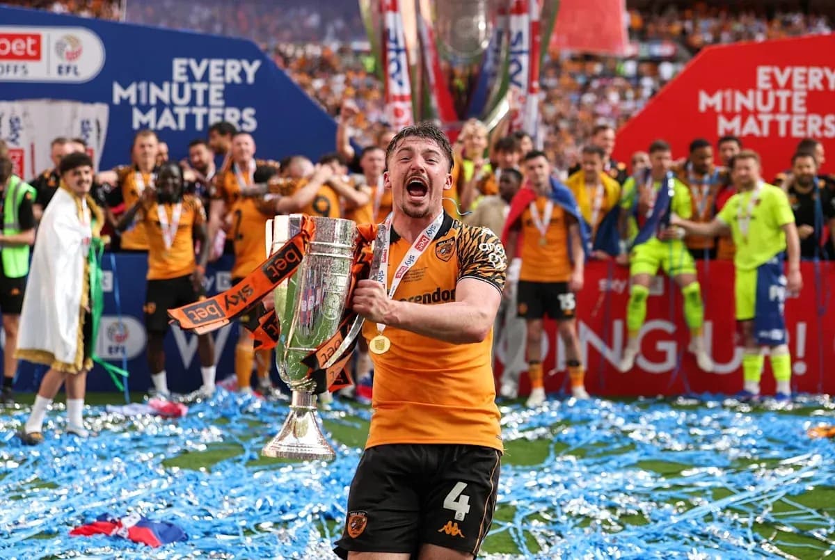 Player celebrating with trophy and confetti on pitch Player celebrating with trophy and confetti on pitch