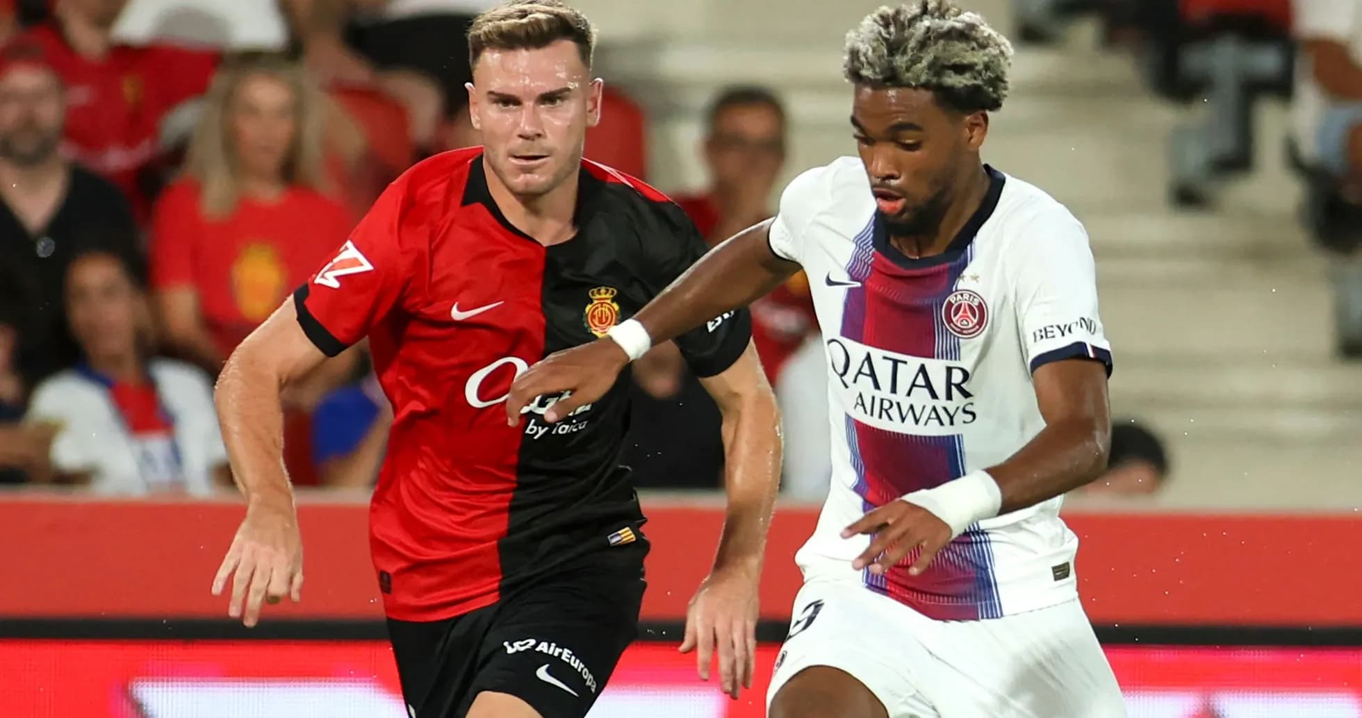 Player from Mallorca chasing PSG player with ball Player from Mallorca chasing PSG player with ball