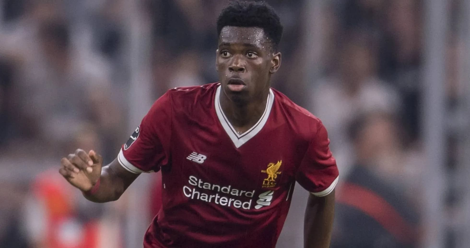 Player in red Liverpool kit running on field Player in red Liverpool kit running on field