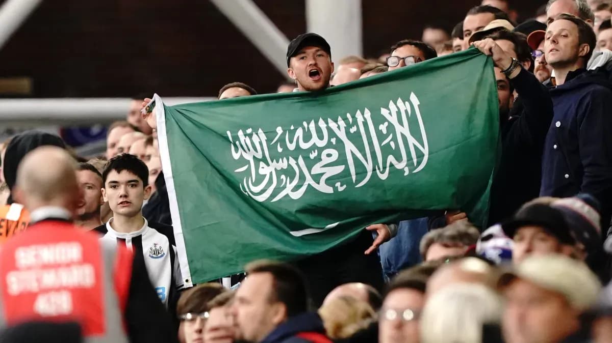 Fan holding Saudi Arabian flag in stadium crowd Fan holding Saudi Arabian flag in stadium crowd