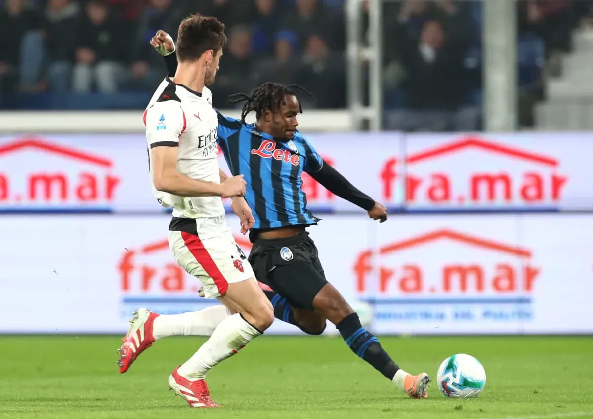 AC Milan player challenges Atalanta player for the ball AC Milan player challenges Atalanta player for the ball
