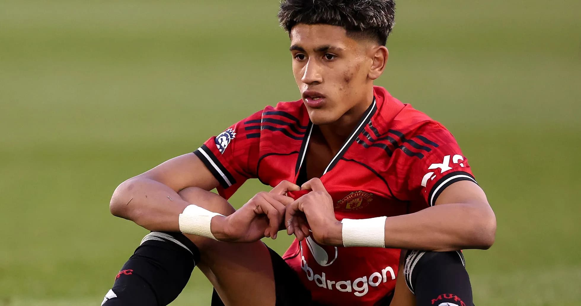 Player sitting on field in Manchester United jersey Player sitting on field in Manchester United jersey