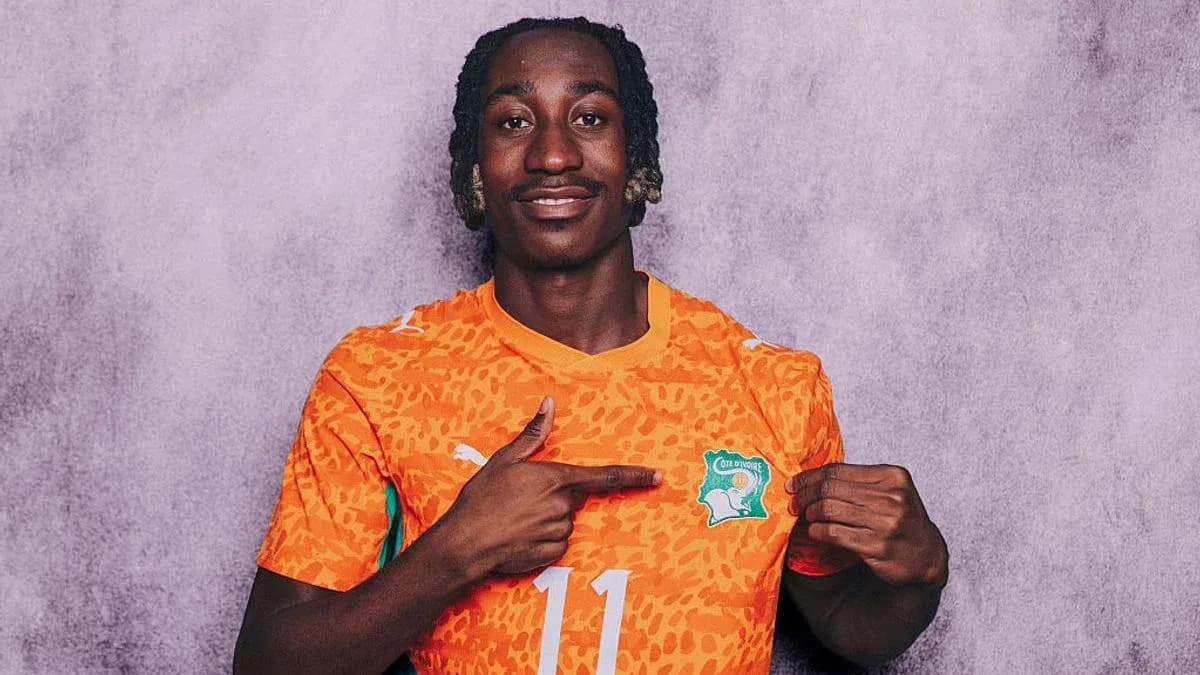Player in orange jersey pointing at national badge Player in orange jersey pointing at national badge