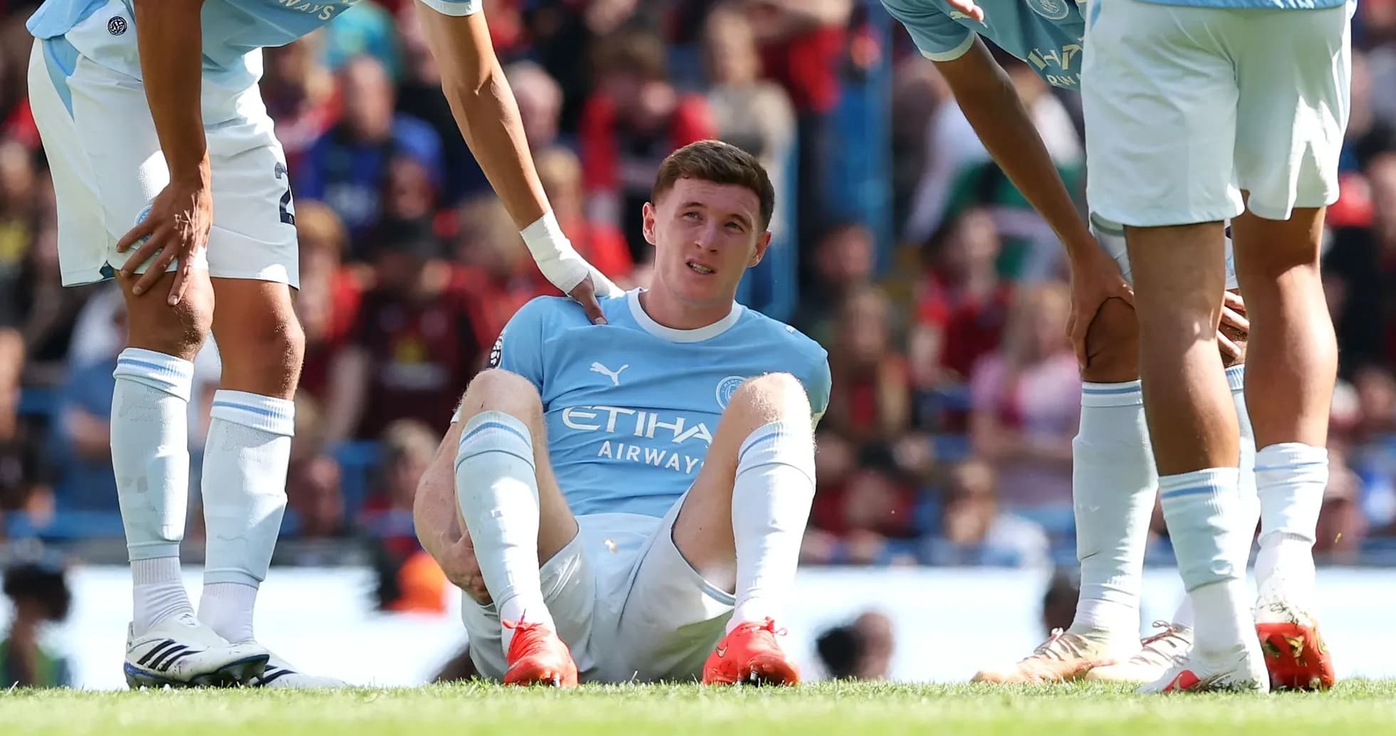 Player sitting on the ground with teammates around Player sitting on the ground with teammates around