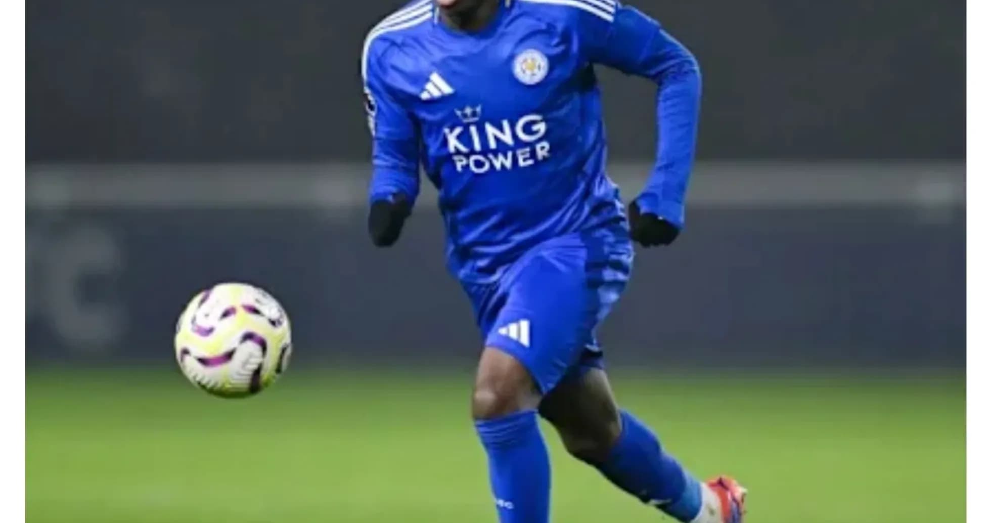 Player in blue kit running with ball on field Player in blue kit running with ball on field