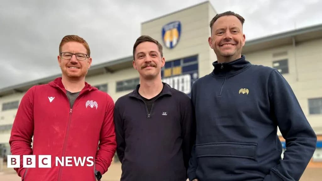 Three men posing in front of sports venue Three men posing in front of sports venue