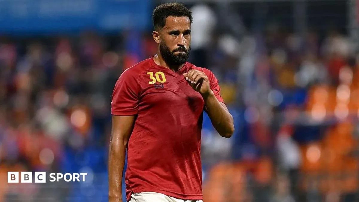 Player in red jersey walking on the pitch Player in red jersey walking on the pitch