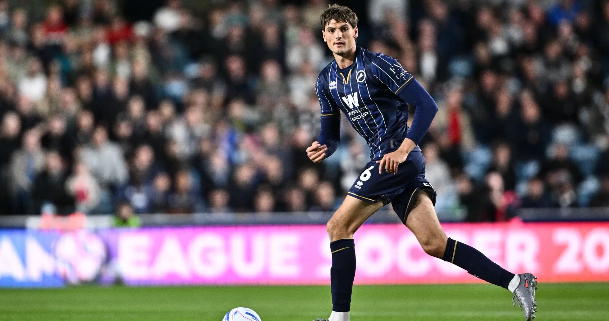 Player in blue kit running on the pitch Player in blue kit running on the pitch